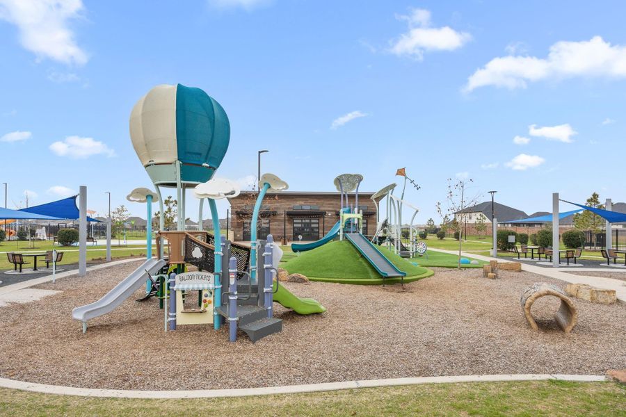 The neighborhood playground includes modern climbing structures, slides, shaded seating, and open green space.