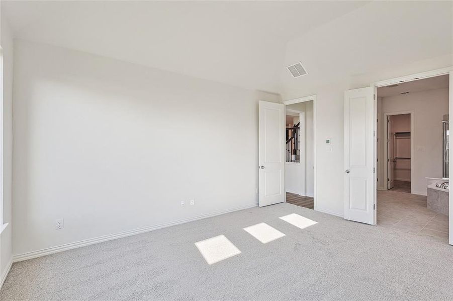 Unfurnished bedroom featuring light carpet and connected bathroom