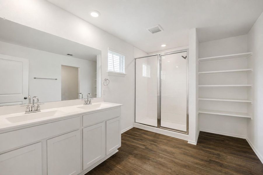 Bathroom featuring a double vanity with white cabinetry, polished chrome faucets, and an expansive mirror Bathroom featuring a double vanity with white cabinetry, polished chrome faucets, and an expansive mirror