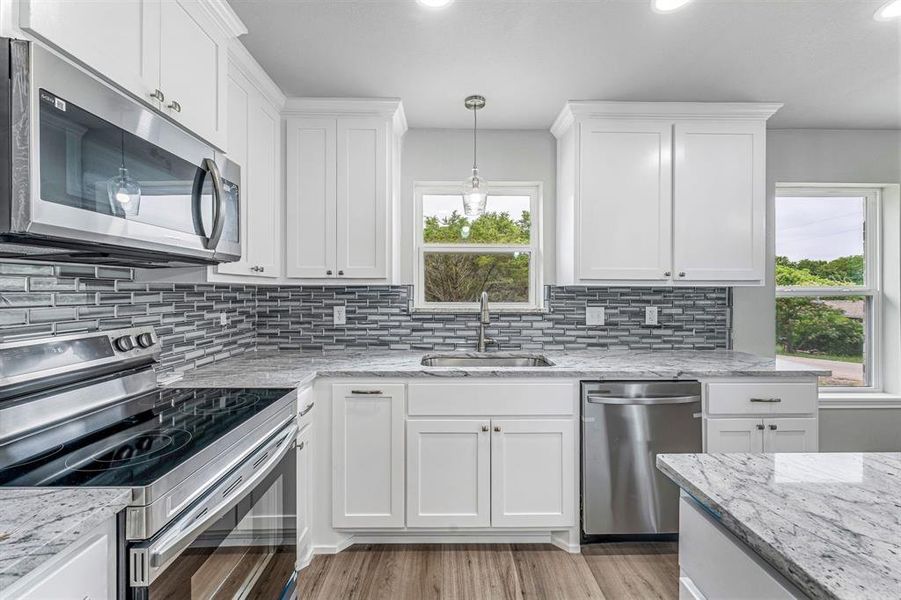 Kitchen with appliances with stainless steel finishes, a sink, plenty of natural light, white cabinets, and recessed lighting Kitchen with appliances with stainless steel finishes, a sink, plenty of natural light, white cabinets, and recessed lighting