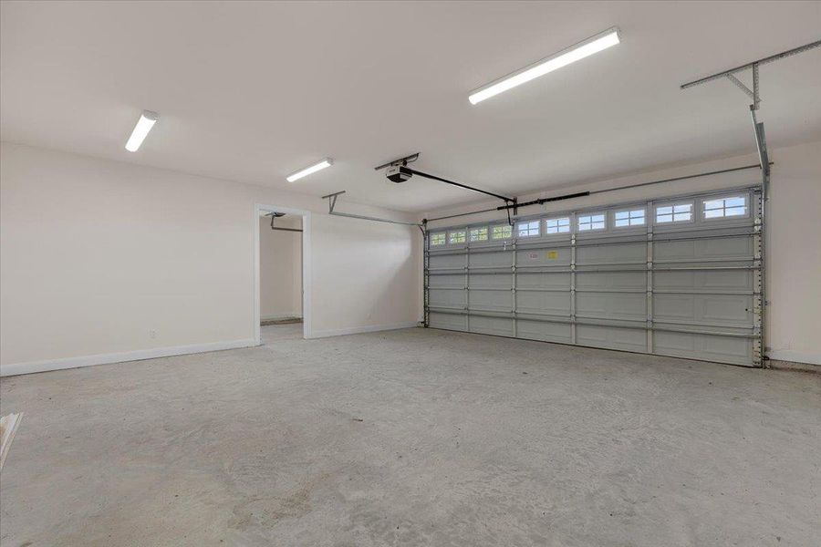 Garage featuring baseboards and a garage door opener