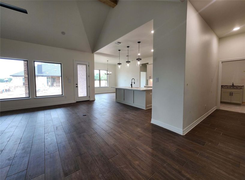 Spacious living area featuring wood-finish flooring, vaulted ceilings, and a ceiling fan
