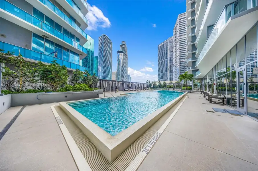 Rectangular swimming pool with light-toned concrete decking, concrete retaining walls, and integrated drainage channels