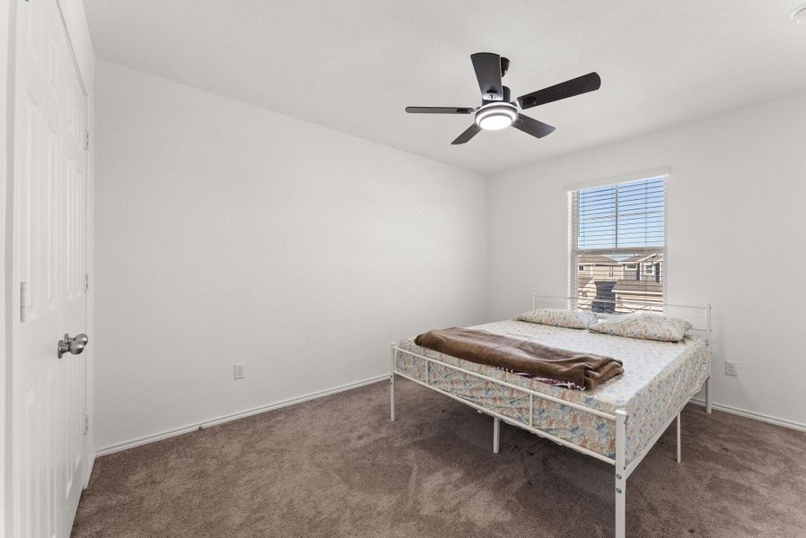 Carpeted bedroom featuring ceiling fan and baseboards