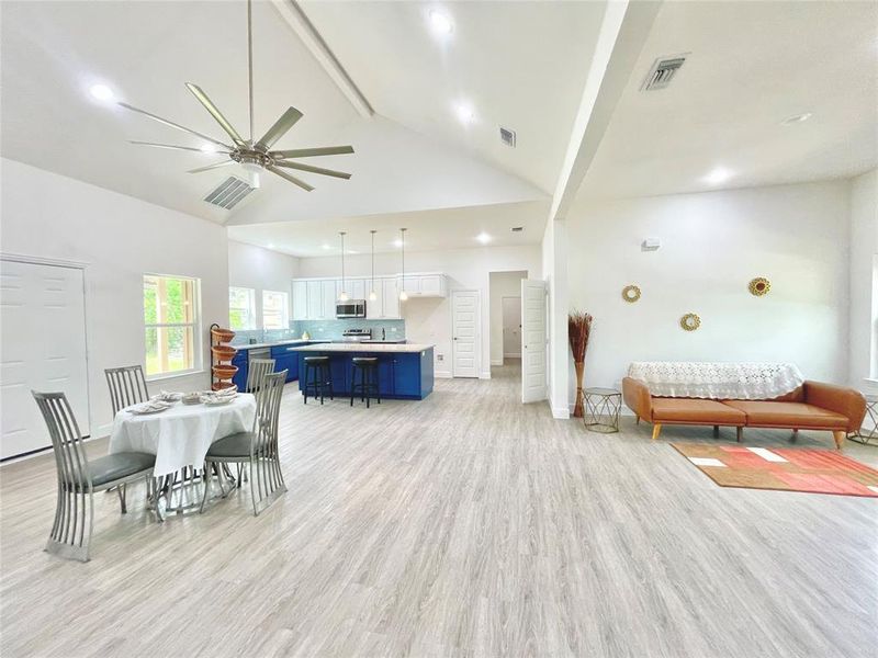 Dining space featuring light wood-style floors, visible vents, beamed ceiling, ceiling fan, and high vaulted ceiling