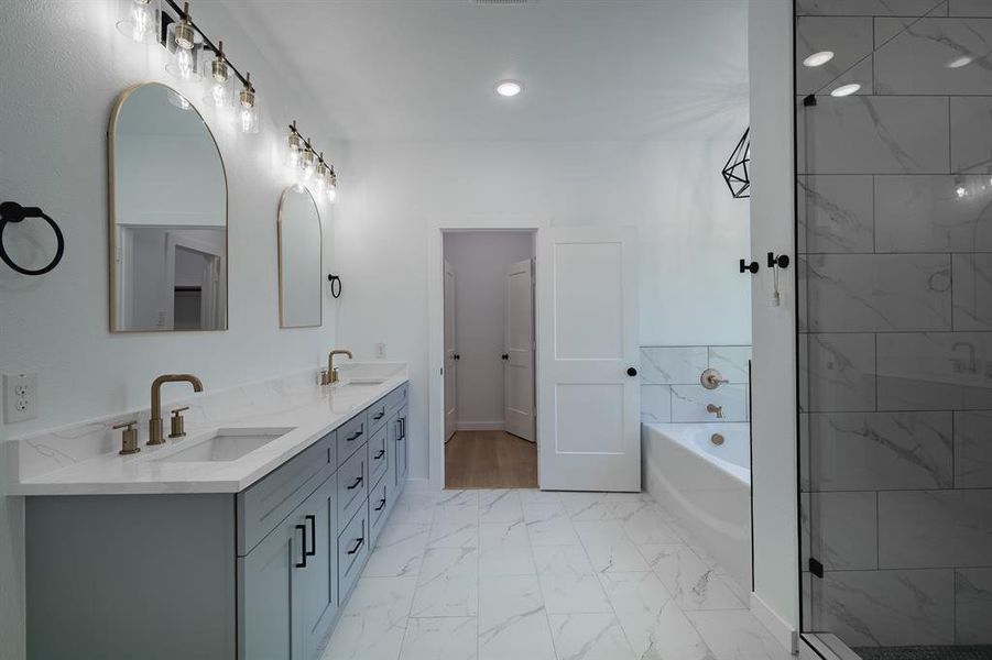 Bathroom featuring double vanity, a garden tub, marble look tile flooring, and a stall shower Bathroom featuring double vanity, a garden tub, marble look tile flooring, and a stall shower