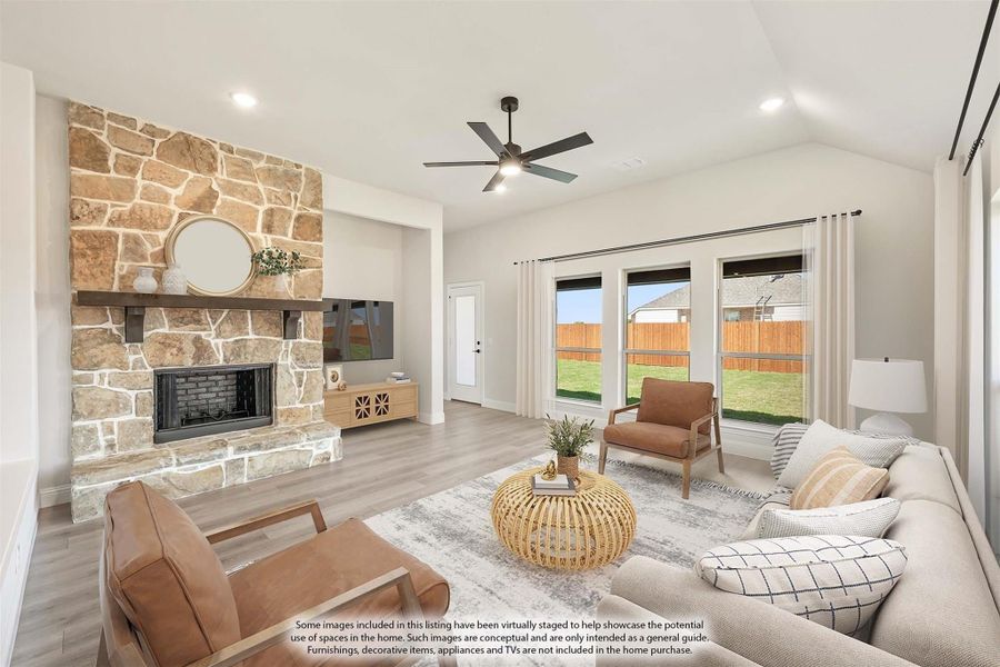 Living room with floor-to-ceiling stone fireplace, vaulted ceiling, ceiling fan, and hardwood floors Living room with floor-to-ceiling stone fireplace, vaulted ceiling, ceiling fan, and hardwood floors
