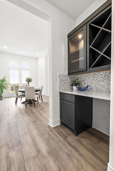 Bar with decorative backsplash, light wood-style flooring, and recessed lighting