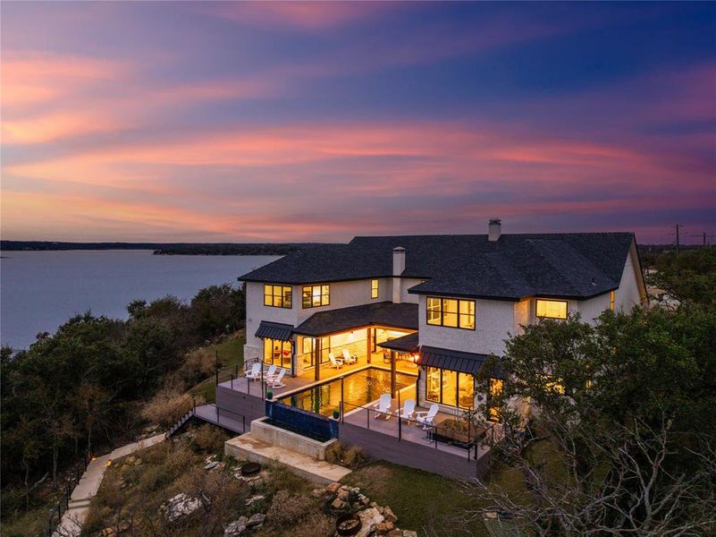Back of house at dusk with a standing seam roof, a chimney, a metal roof, outdoor lounge area, and a deck with water view