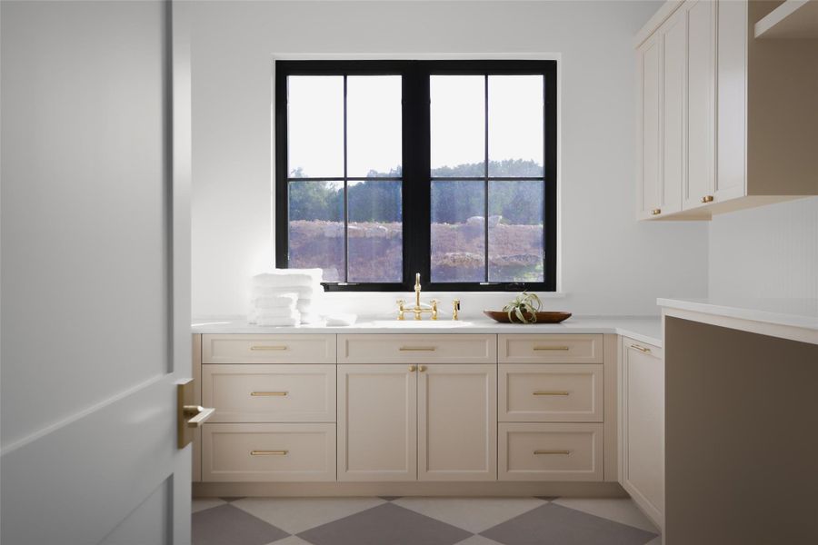 A functional mudroom and laundry hub. This isn't just a utility closet; the expansive laundry room offers massive counter space for folding, a dedicated soaking sink, and built-in cabinetry. Its location near the garage entry makes it the perfect "drop zone" for a busy lifestyle.
