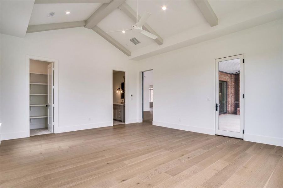 Unfurnished bedroom with a spacious closet, light wood-type flooring, beamed ceiling, baseboards, and visible vents