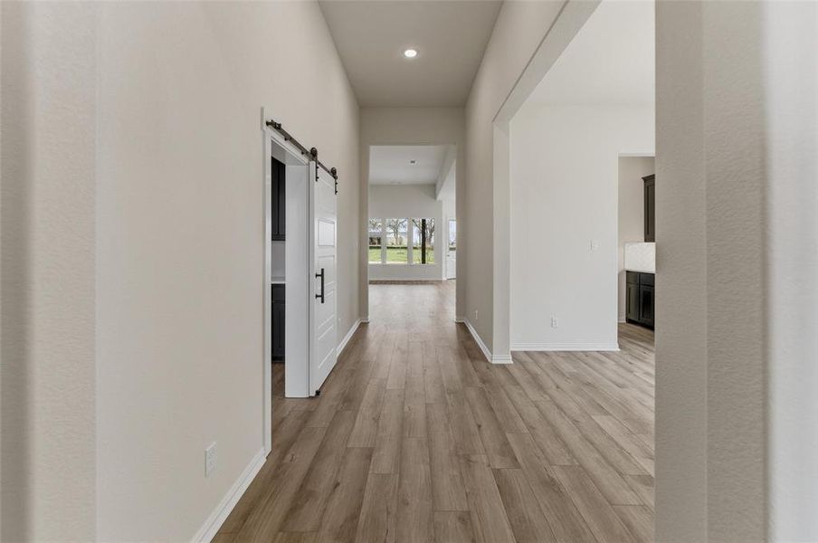 Hallway featuring a barn door, light wood finished floors, and recessed lighting