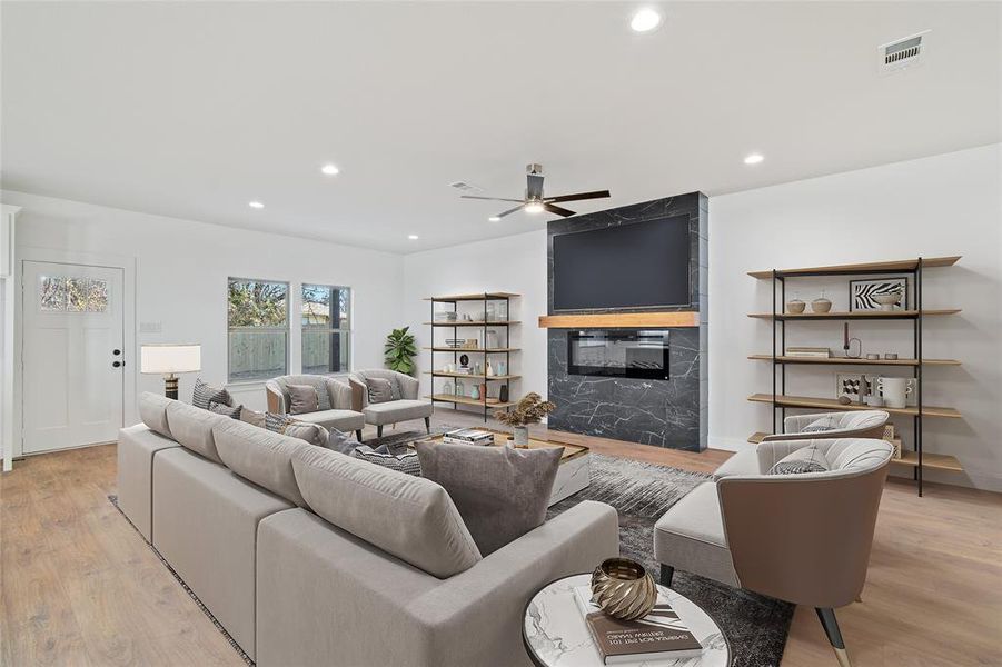 Living room with ceiling fan, light hardwood / wood-style floors, and a fireplace