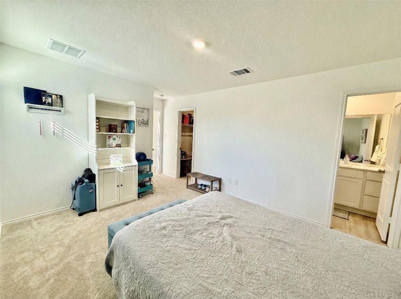 Bedroom with a textured ceiling, light colored carpet, and a spacious closet