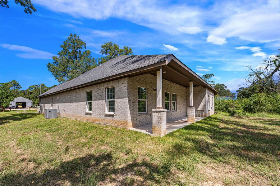 Covered back patio with brick columns and yard view.