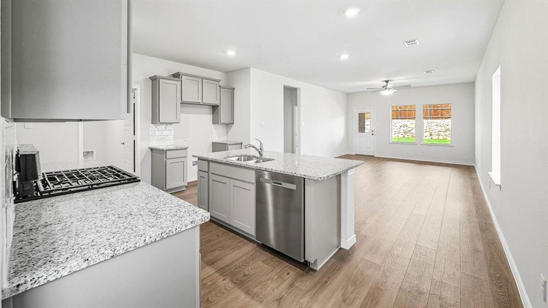 Kitchen with light stone counters, gray cabinets, dishwasher, a kitchen island with sink, and dark wood-type flooring