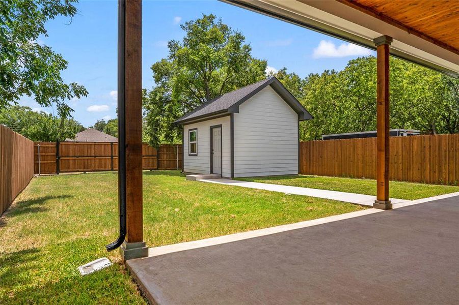 Fenced backyard with an outbuilding and a patio area Fenced backyard with an outbuilding and a patio area