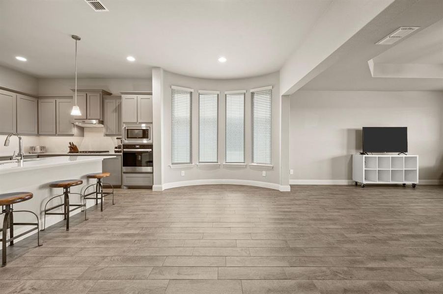 Spacious dining area with a beautiful curved wall of windows, open to the kitchen and living room for seamless entertaining.