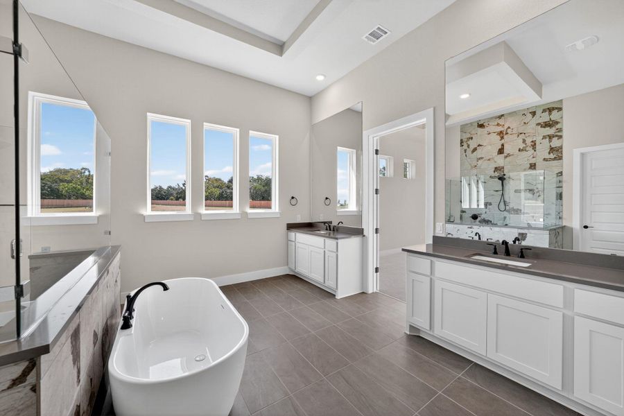 Full bathroom with a freestanding tub, a marble finish shower, and two vanities Full bathroom with a freestanding tub, a marble finish shower, and two vanities