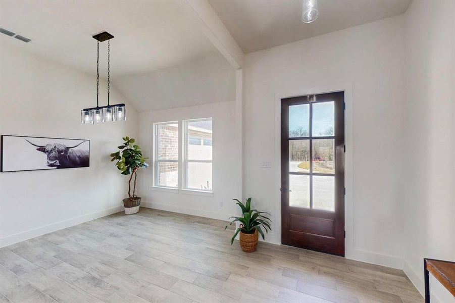 Entrance foyer with vaulted ceiling with beams and light hardwood / wood-style floors