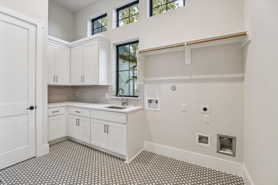 Utility Room with sink, tile backsplash and floor, upper and lower cabinetry, and hanging rod. Utility Room with sink, tile backsplash and floor, upper and lower cabinetry, and hanging rod.