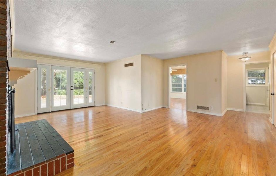 Unfurnished living room featuring light wood-style flooring, a textured ceiling, french doors, and ornamental molding