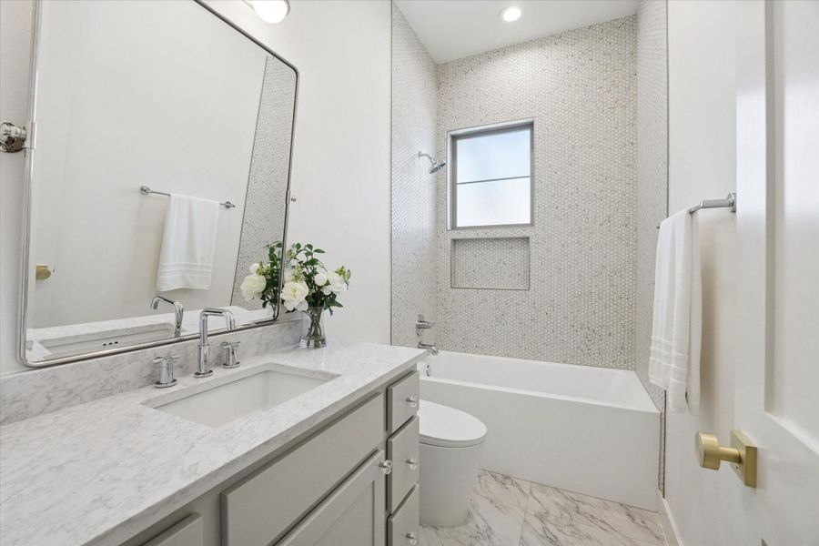 Ensuite bath with a quartz countertop, polished nickel plumbing fixtures and penny porcelain mosaic tile in the shower/ tub combo.