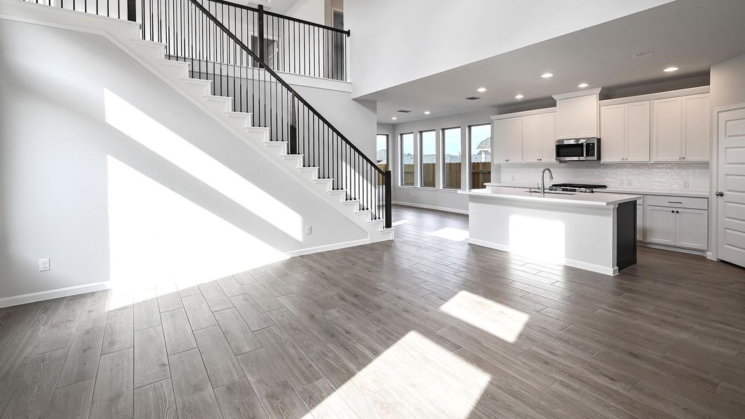 Kitchen featuring white cabinets, a high ceiling, a center island with sink, open floor plan, and recessed lighting Kitchen featuring white cabinets, a high ceiling, a center island with sink, open floor plan, and recessed lighting