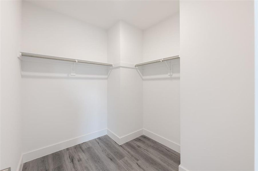 *Representative Photo. Primary Bedroom walk-in closet with ample hanging space, featuring modern gray flooring.