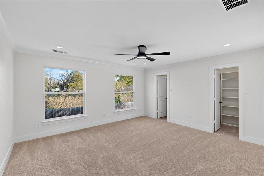 Unfurnished bedroom with a spacious closet, light colored carpet, ornamental molding, a ceiling fan, and recessed lighting