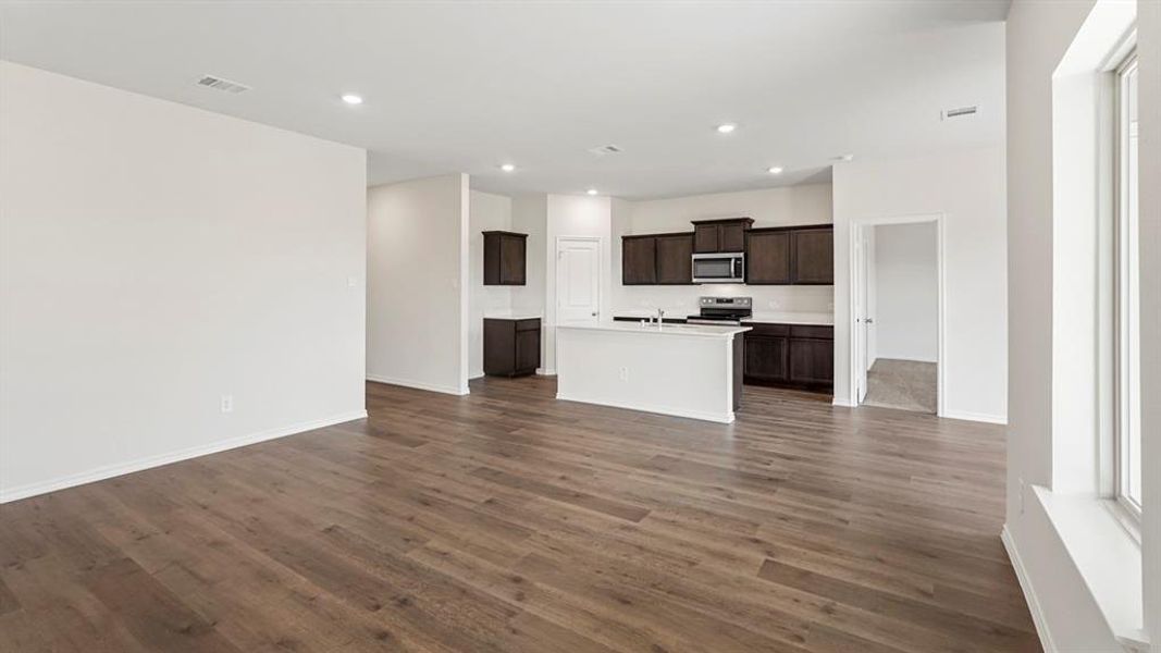 Open-concept living space featuring wood-finish flooring, recessed lighting, and a white interior paint palette