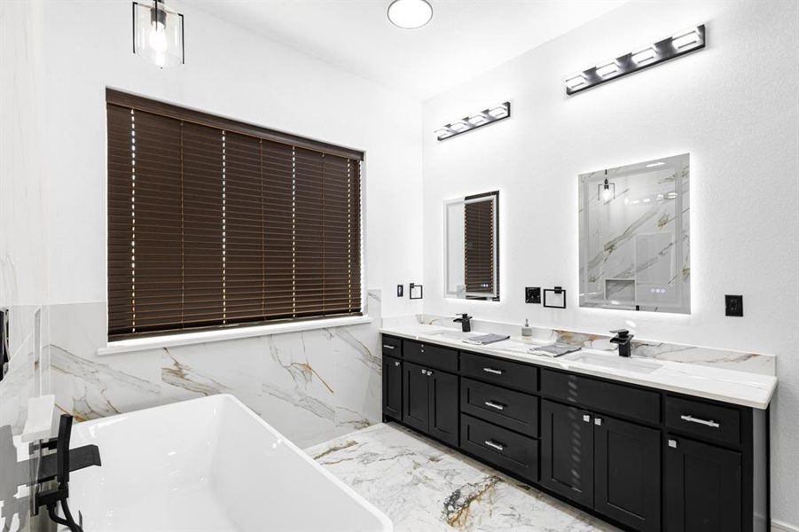 Full bath with a freestanding bath, double vanity, light marble finish floors, and a marble finish shower