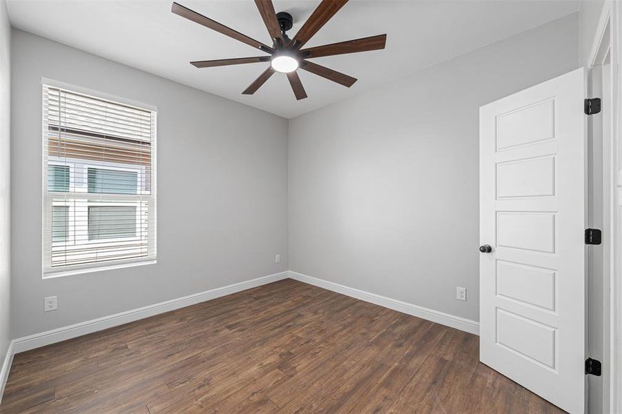 Empty room featuring dark wood-type flooring and ceiling fan