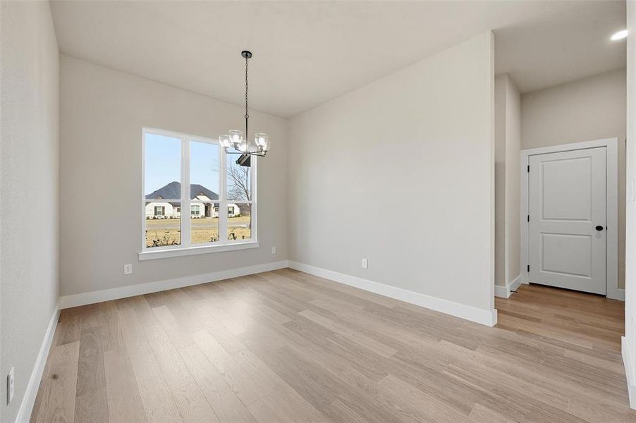 Unfurnished dining area featuring suspended lighting and light wood-style flooring