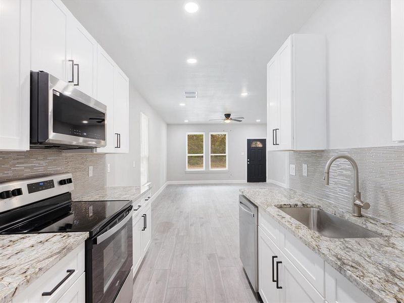 Kitchen featuring backsplash, appliances with stainless steel finishes, white cabinetry, and recessed lighting