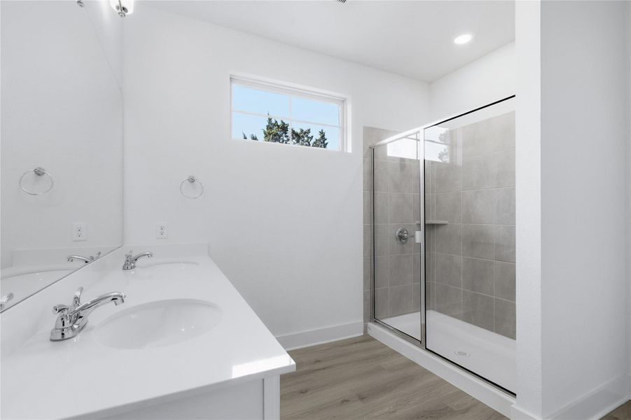 Bathroom featuring a stall shower, light wood-style floors, and double vanity