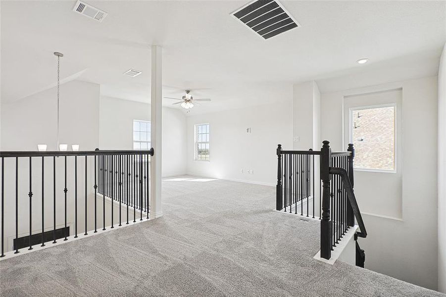 Hallway featuring light carpet, an inviting chandelier, and a healthy amount of sunlight