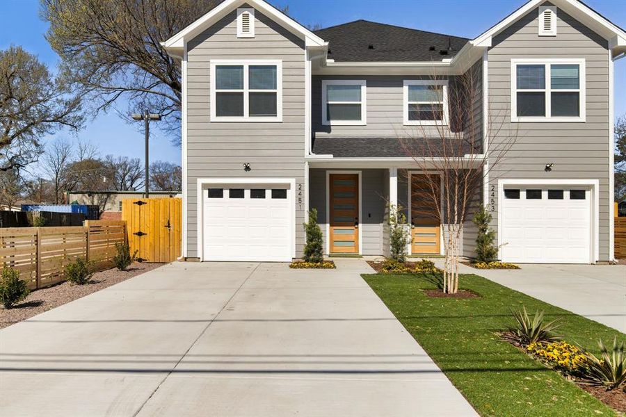 View of front facade with a shingled roof, driveway, an attached garage, and fence