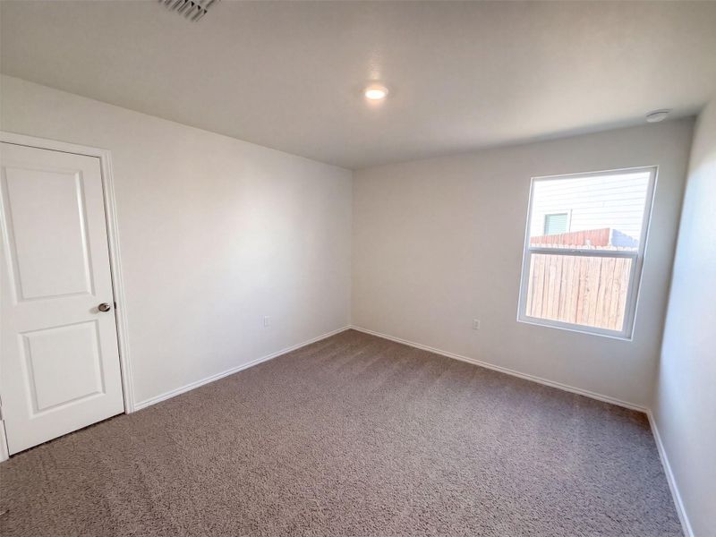 Soft carpeted flooring and a bright single window anchor this versatile bedroom space.