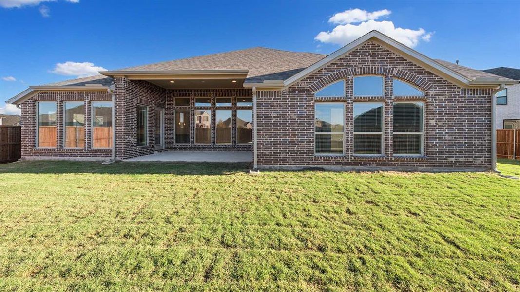 Rear view of house featuring a patio and a lawn