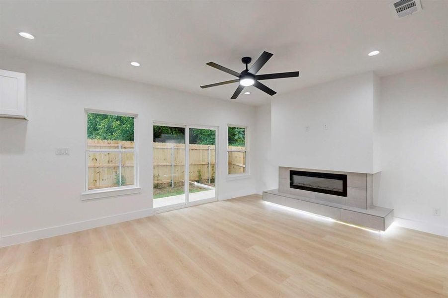 Unfurnished living room featuring recessed lighting, light wood-style floors, a fireplace, and a ceiling fan Unfurnished living room featuring recessed lighting, light wood-style floors, a fireplace, and a ceiling fan