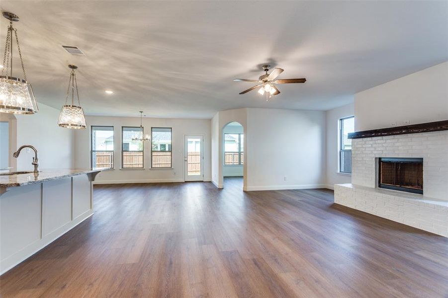 Unfurnished living room featuring a fireplace, dark hardwood / wood-style floors, sink, and ceiling fan