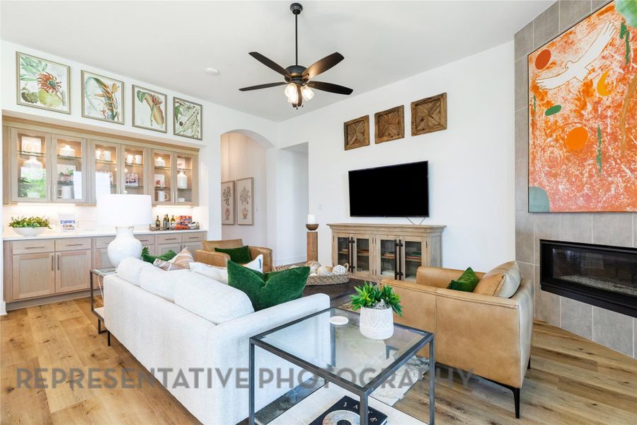 Living area featuring a fireplace, light wood-style floors, arched walkways, and ceiling fan Living area featuring a fireplace, light wood-style floors, arched walkways, and ceiling fan