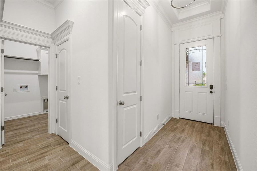 Entryway featuring wood-look tile flooring, white walls, and a front door with decorative glass