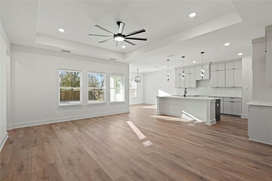 Unfurnished living room with recessed lighting, a raised ceiling, visible vents, and light wood finished floors