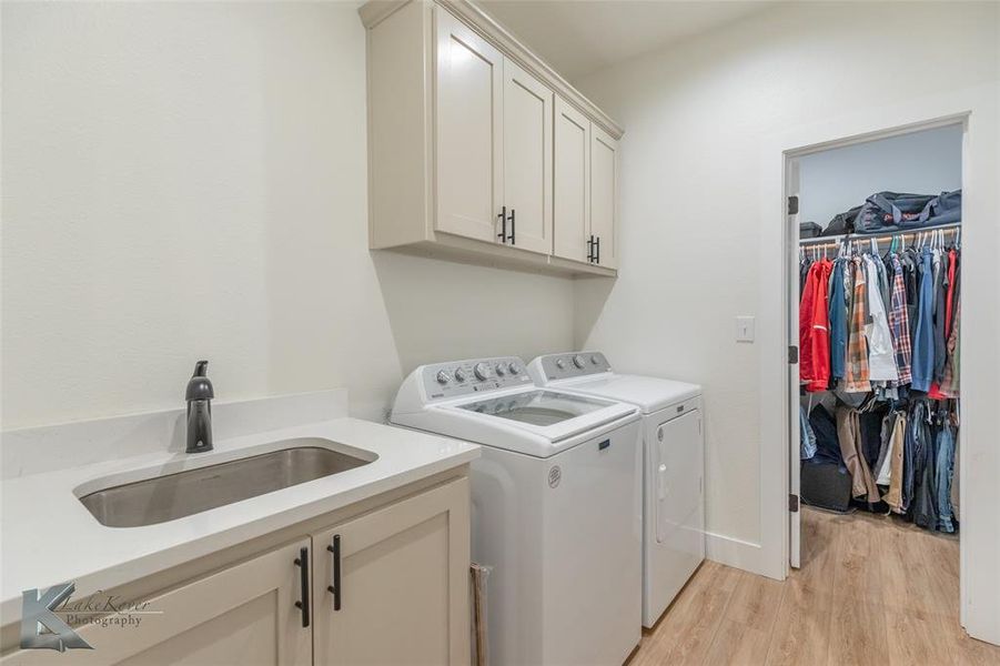 Washroom featuring light wood-style floors, washing machine and dryer, and cabinet space Washroom featuring light wood-style floors, washing machine and dryer, and cabinet space