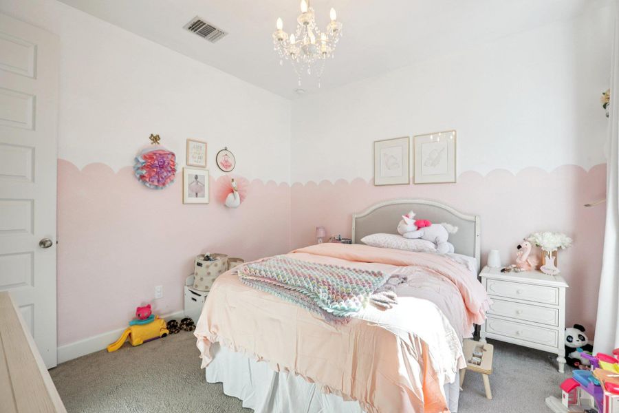 Carpeted bedroom with a chandelier and baseboards