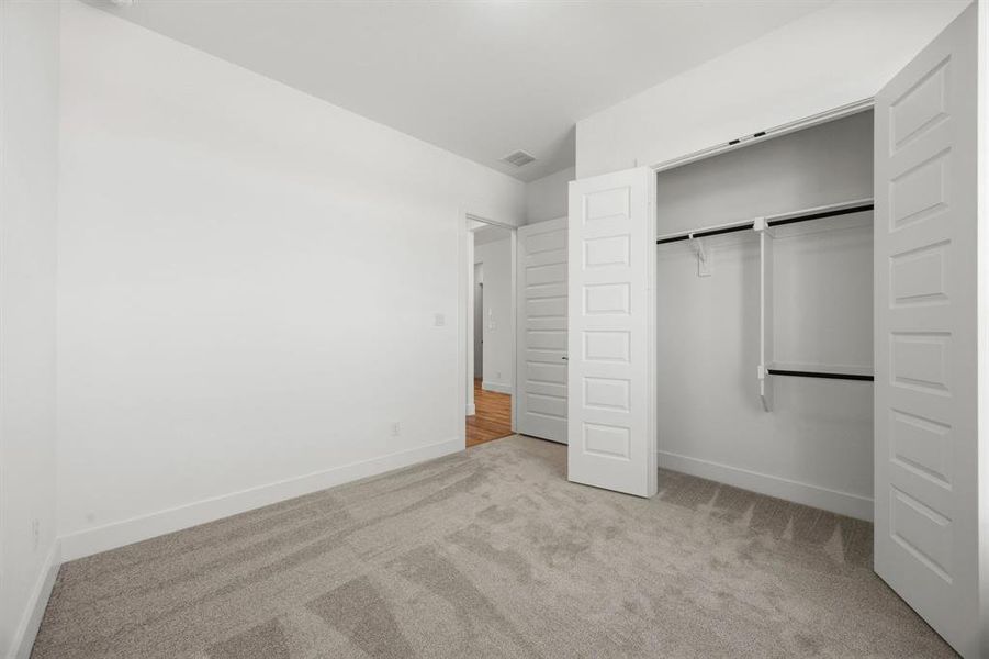Unfurnished bedroom with light carpet and a closet