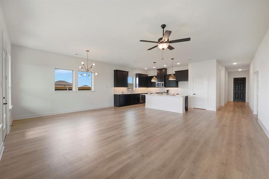 Unfurnished living room featuring suspended lighting, ceiling fan, and light wood-style floors Unfurnished living room featuring suspended lighting, ceiling fan, and light wood-style floors