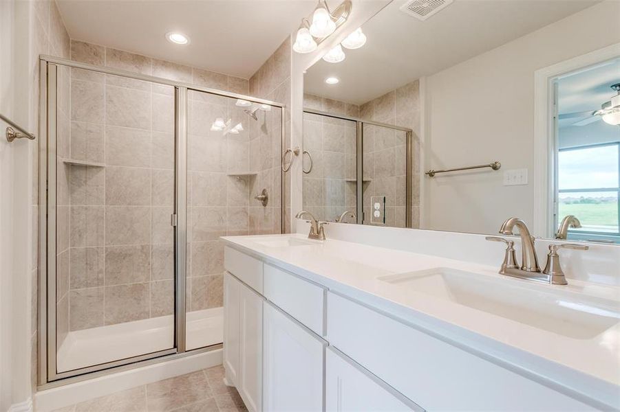 Bathroom with ceiling fan, vanity, a shower with shower door, and tile patterned flooring